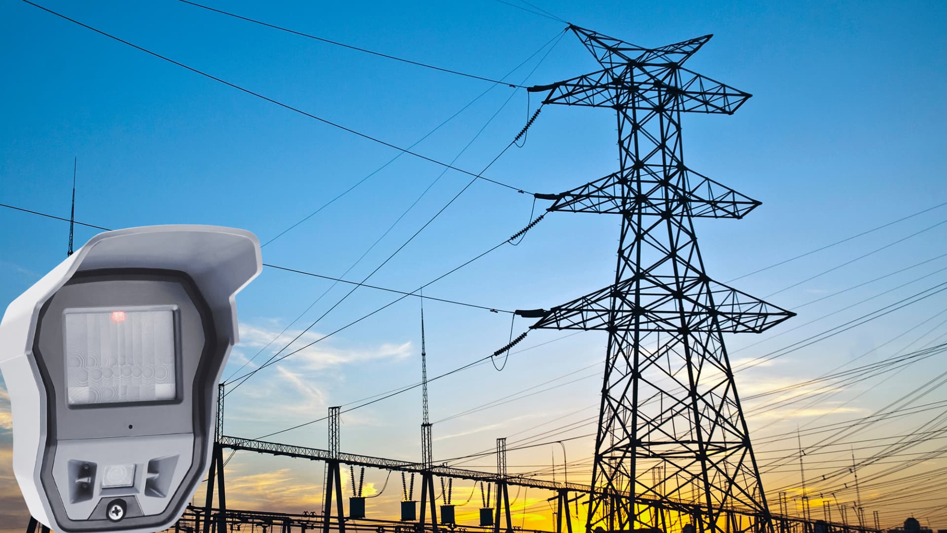 Electrical substation with security fencing and surveillance cameras at dusk